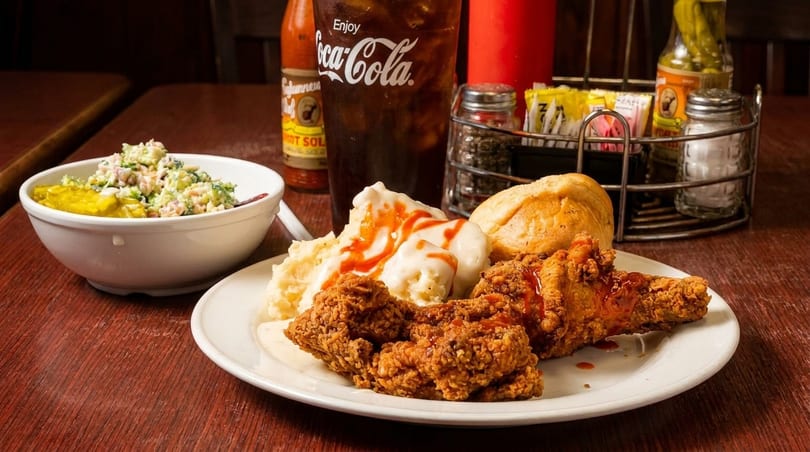 Crispy fried chicken, mashed potatoes, gravy, a roll, and broccoli salad with a Coca-Cola.